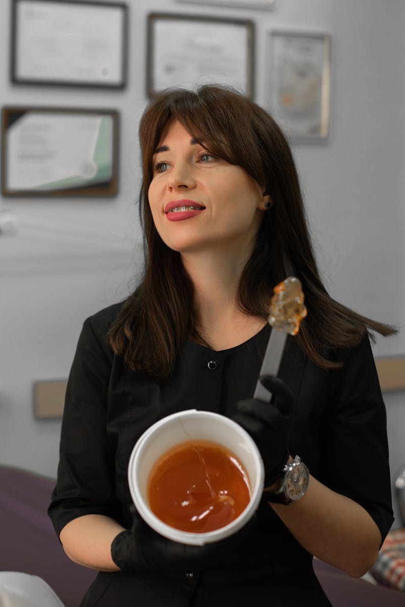 Brunette woman holds honey jar indoors, showcasing food therapy concept.